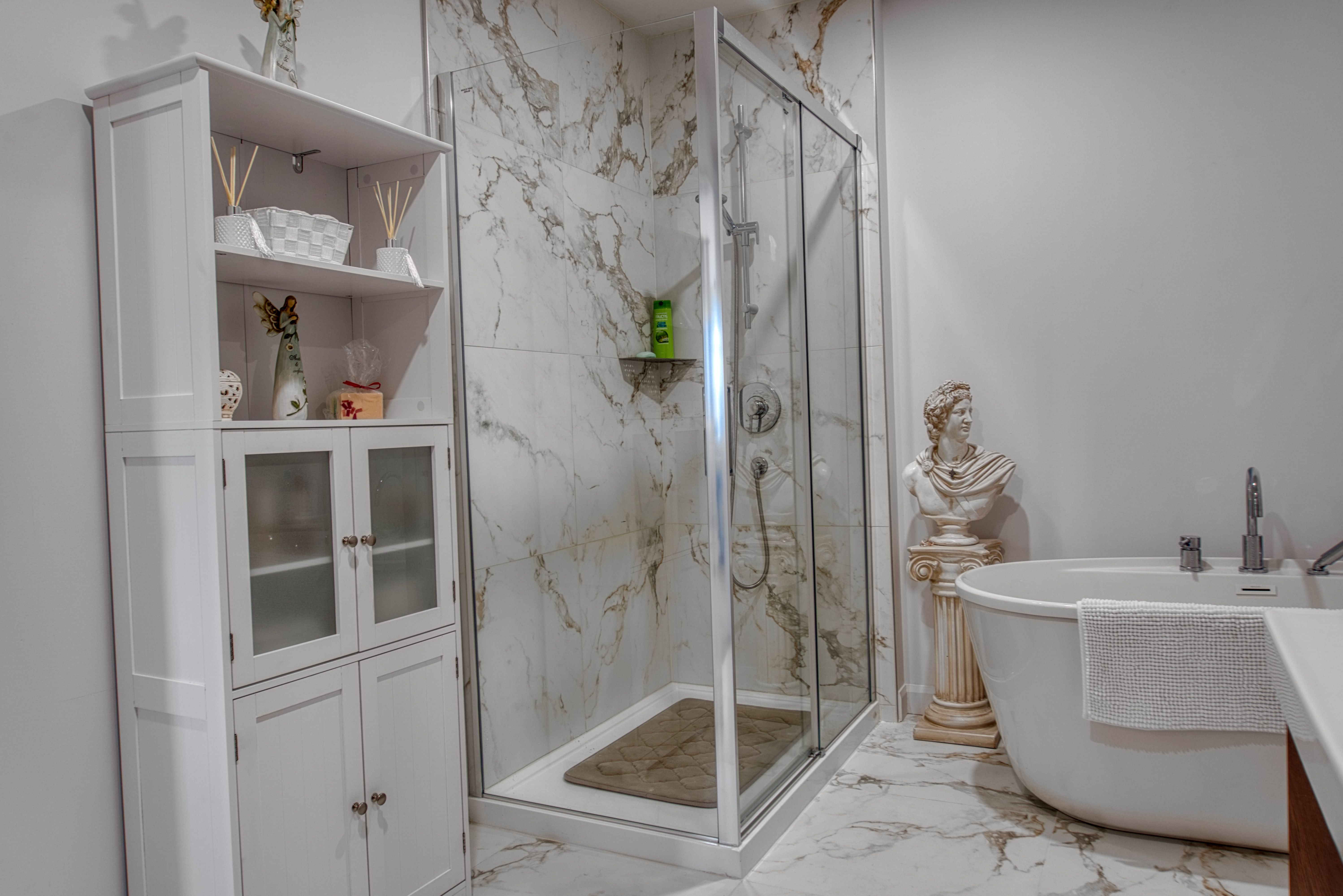 Salle de bain en céramique effet marbre, douche vitrée et bain autoportant